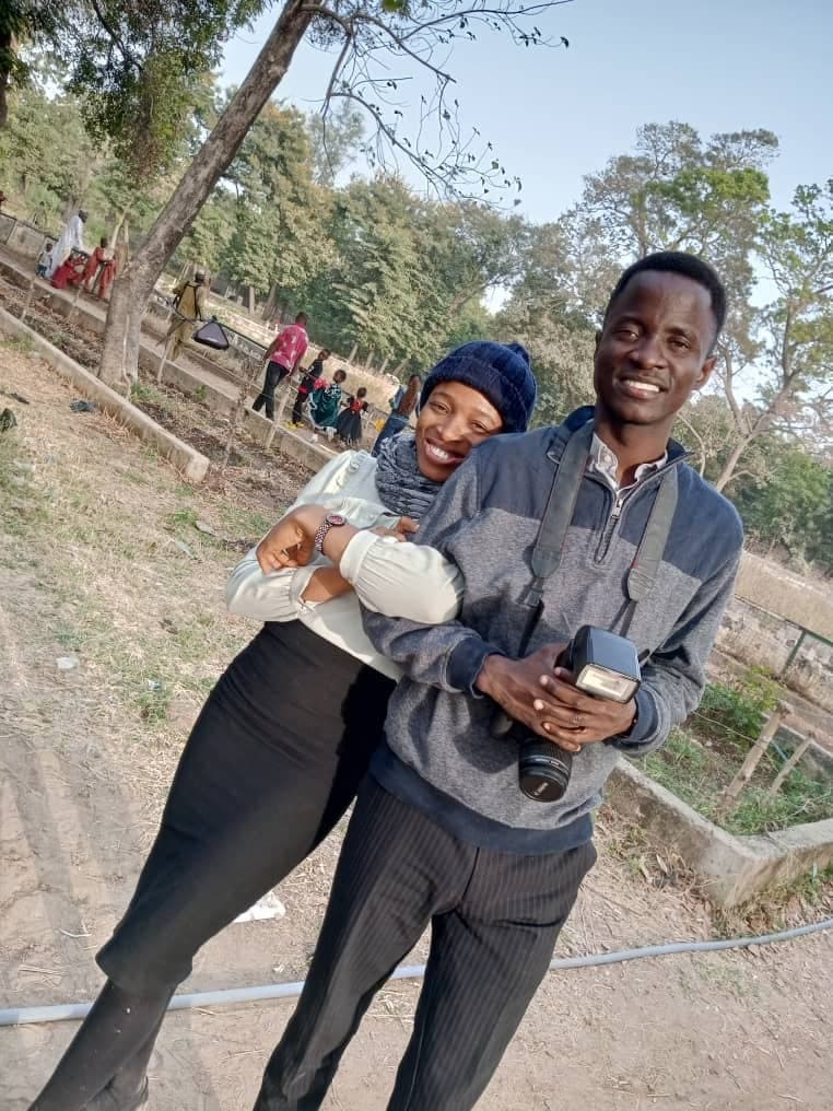 Scholarstica in a knit beanie holding Joseph's arm as he holds a DSLR camera